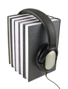 Audio-books concept composition as a stack of books with a headphones on it, isolated over white background